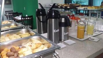 Un buffet con diversi cibi e bevande, tra cui una postazione caffè con tazze termiche a marchio.