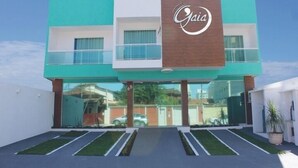 A modern building with a prominent logo, large glass windows, and a well-maintained entrance area. - Gaia Suites Macaé (Macaé)
