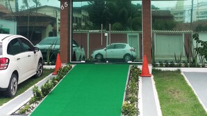 A building with a sign reading "Gaia Suites" and a green artificial lawn in front. - Gaia Suites Macaé (Macaé)