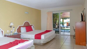 A hotel room with two beds, a desk, a chair, and a view of the outdoor area. - Hotel JS (Yautepec)