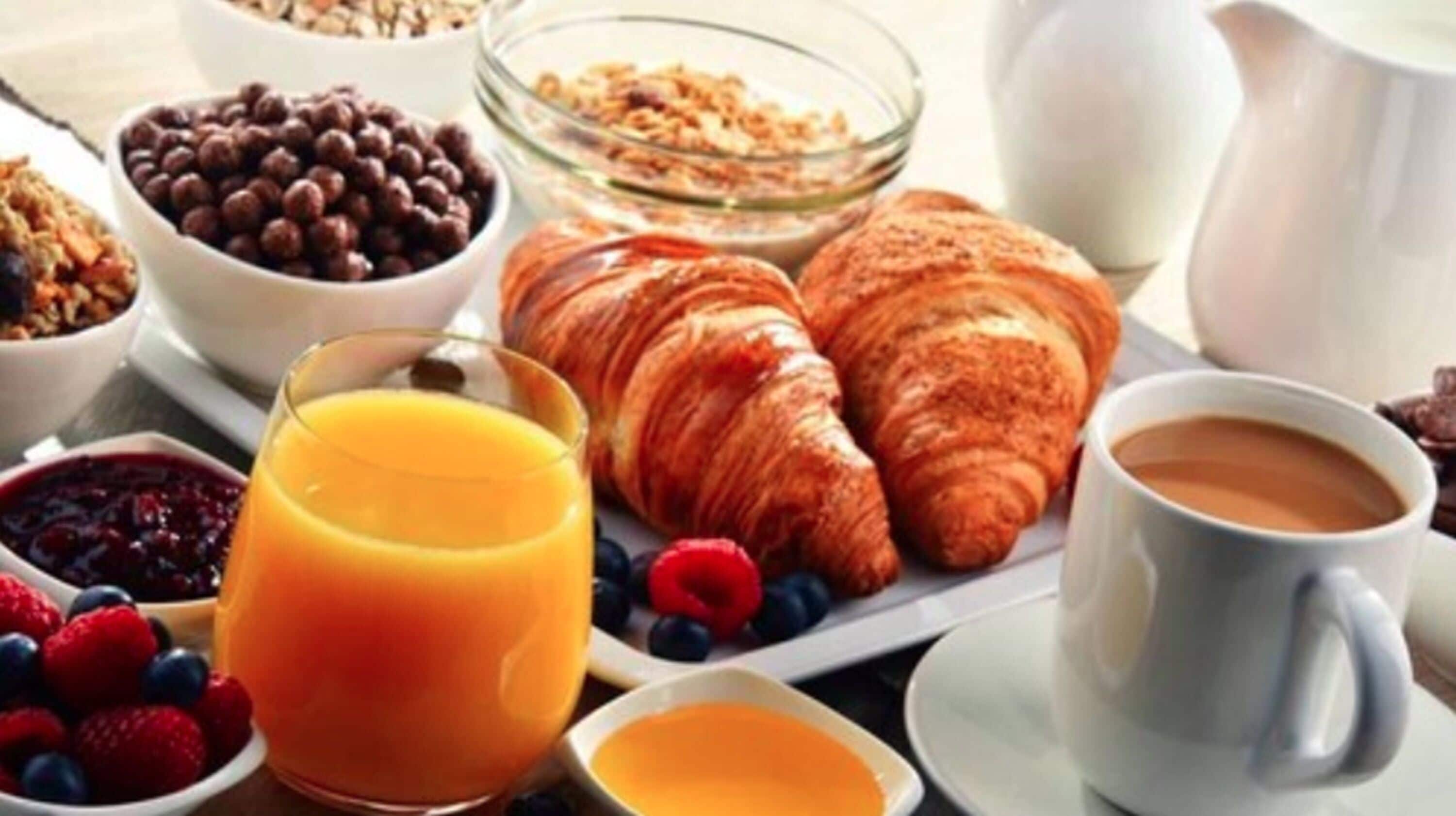 A breakfast setting with croissants, coffee, and various fruits and cereals.