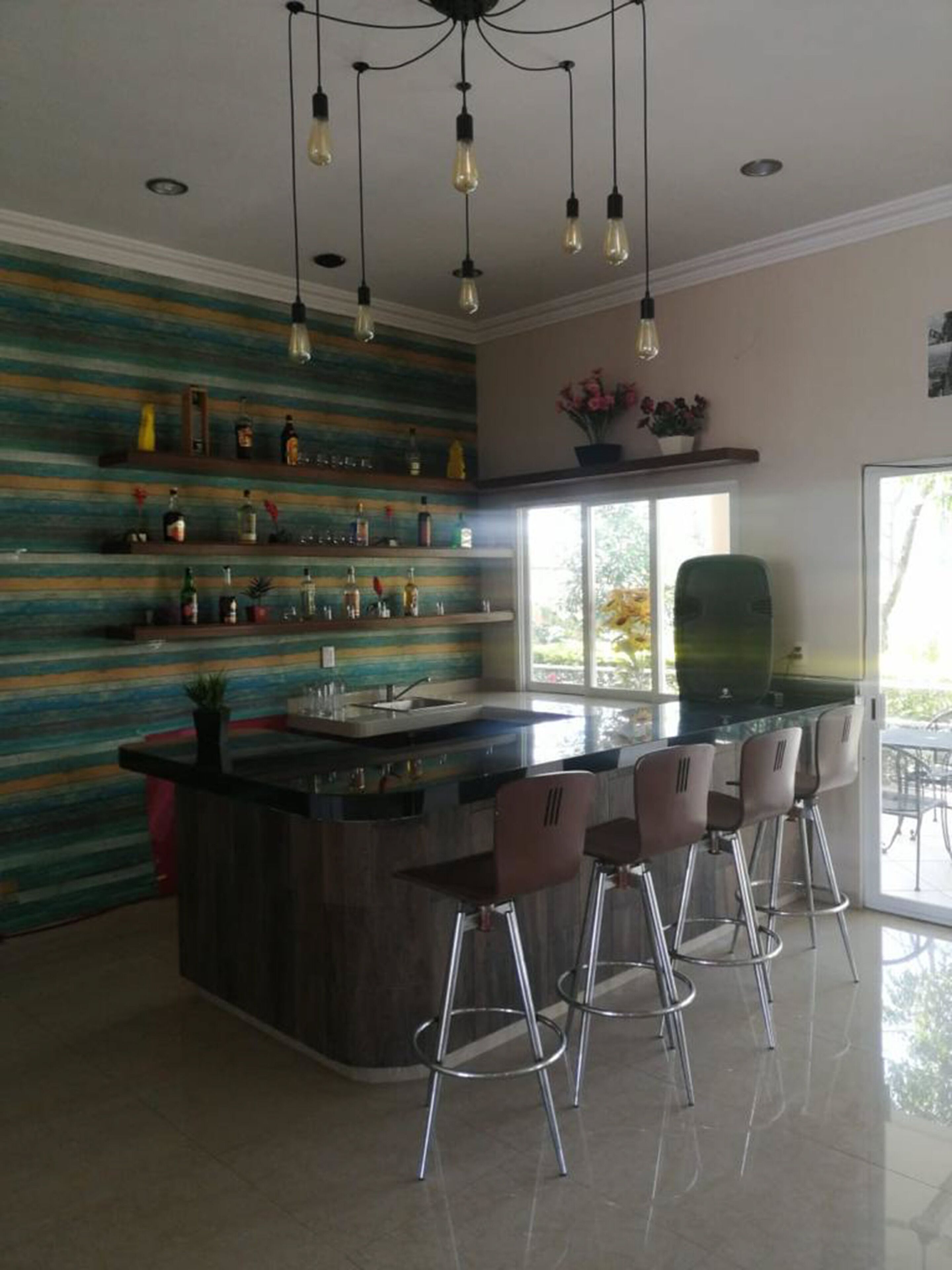 A modern kitchen with a central island, bar stools, and a decorative wall with shelves.