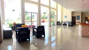 A hotel lobby with a reception desk, seating area, and large windows. - Hotel JS (Yautepec)