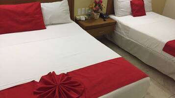 Dos camas con sábanas blancas y detalles rojos, una mesita de noche con un teléfono y un florero, y un cabecero de madera.