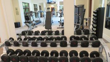 Une salle de sport équipée de divers appareils d’exercice, notamment des haltères et des tapis de course.