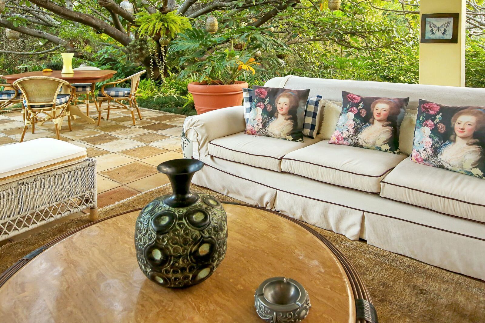 A cozy outdoor seating area with a wicker sofa, a round coffee table, and a potted plant.