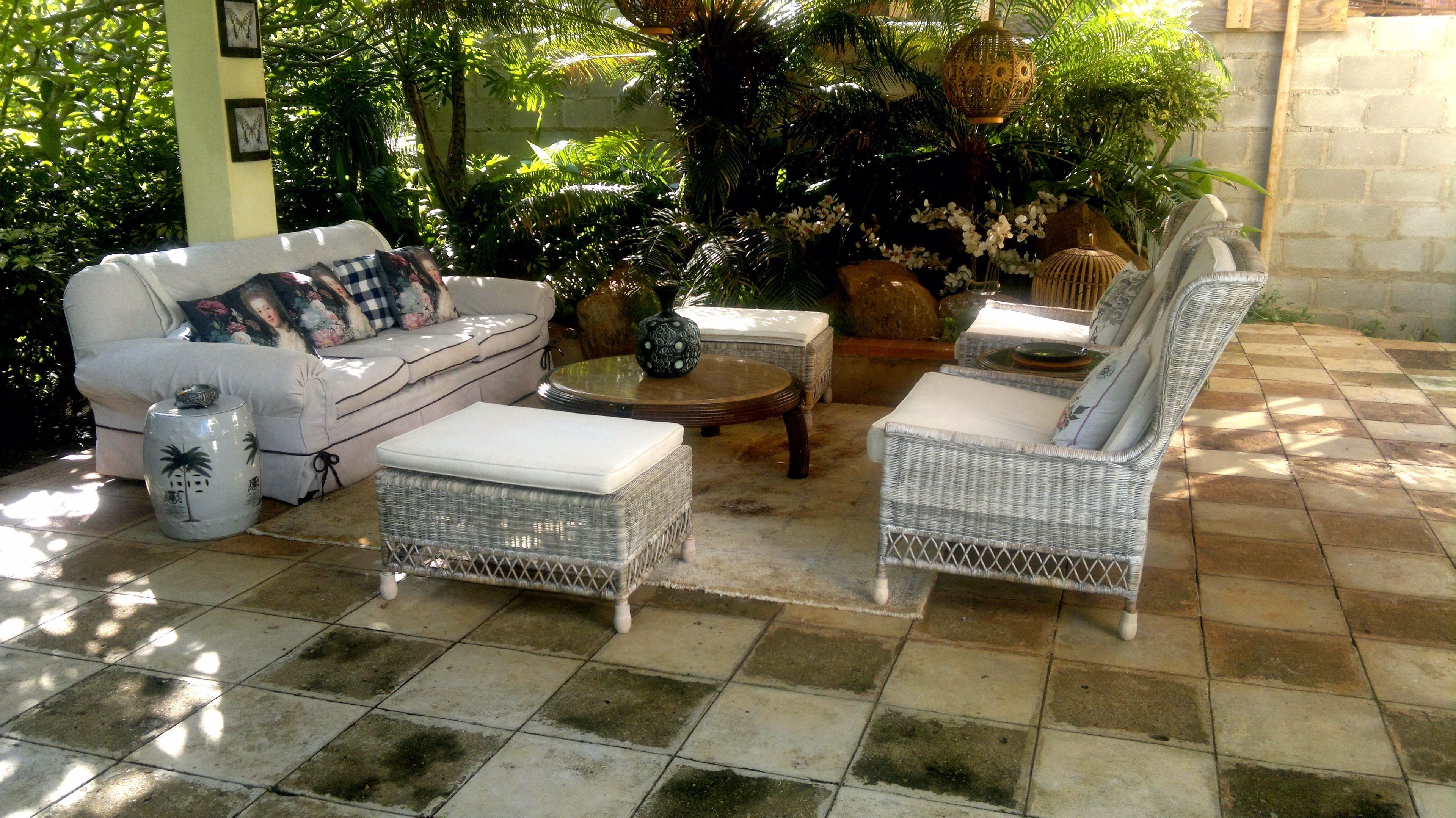 A patio with wicker furniture, a white sofa, and a decorative vase.