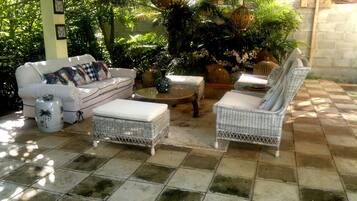 A patio with wicker furniture, a white sofa, and a decorative vase.