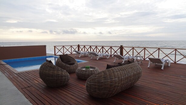 A wooden deck with lounge chairs and a pool, overlooking the sea. - Casa de Playa Akas (Canoas de Punta Sal)