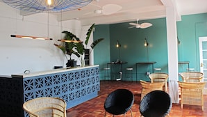 A modern interior with a reception desk, wicker chairs, and ceiling fans.