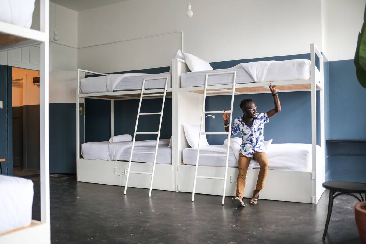 Habitación con literas, ropa de cama blanca y una escalera.