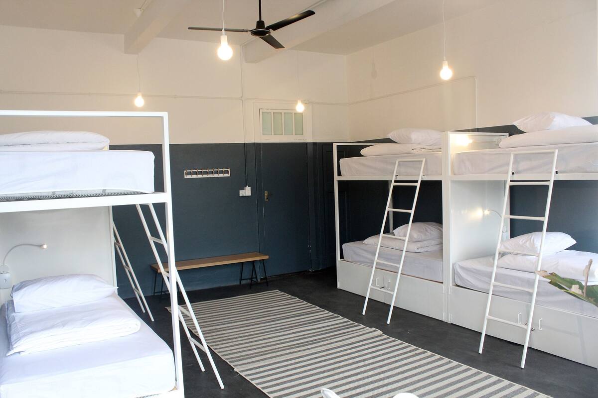 Un dormitorio con literas, un escritorio y un ventilador de techo.