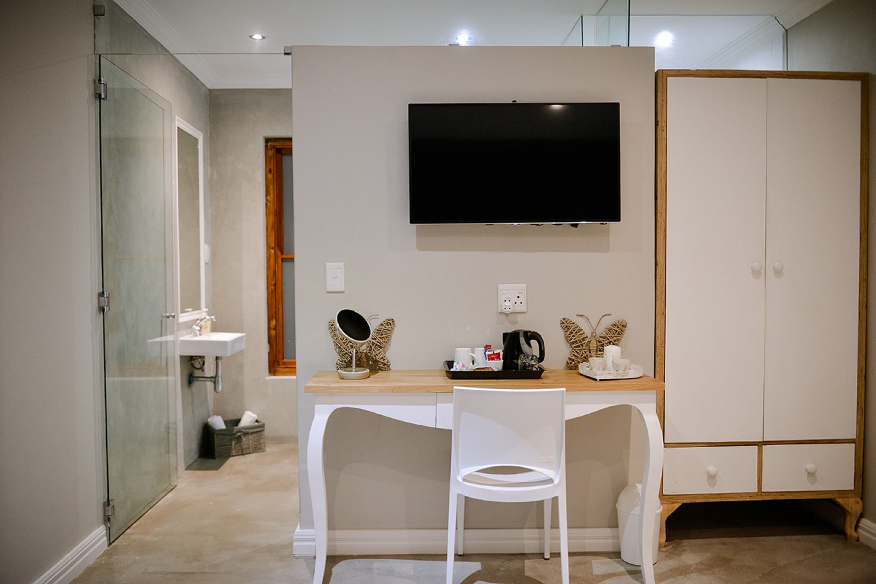 Un baño moderno con cabina de ducha de vidrio, lavabo blanco y tocador.