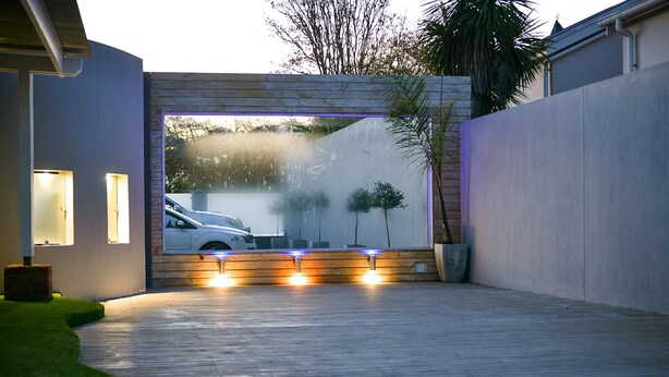 A modern house with a garage door, a driveway, and a well-maintained lawn.