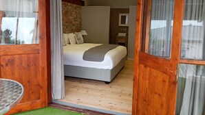 A bedroom with a bed, a nightstand, a lamp, and a window with curtains.