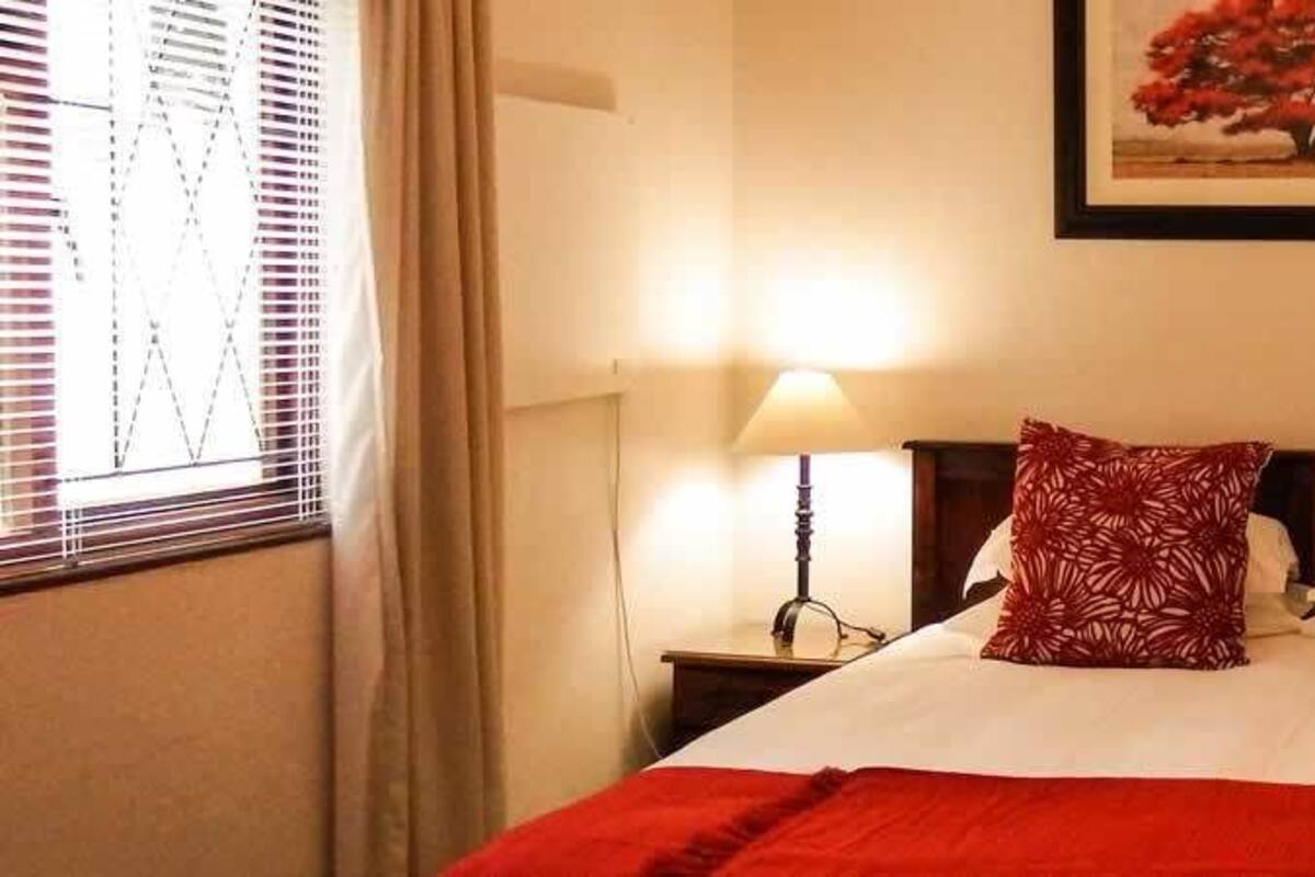 A hotel room with a large bed, two bedside lamps, and a framed picture on the wall.
