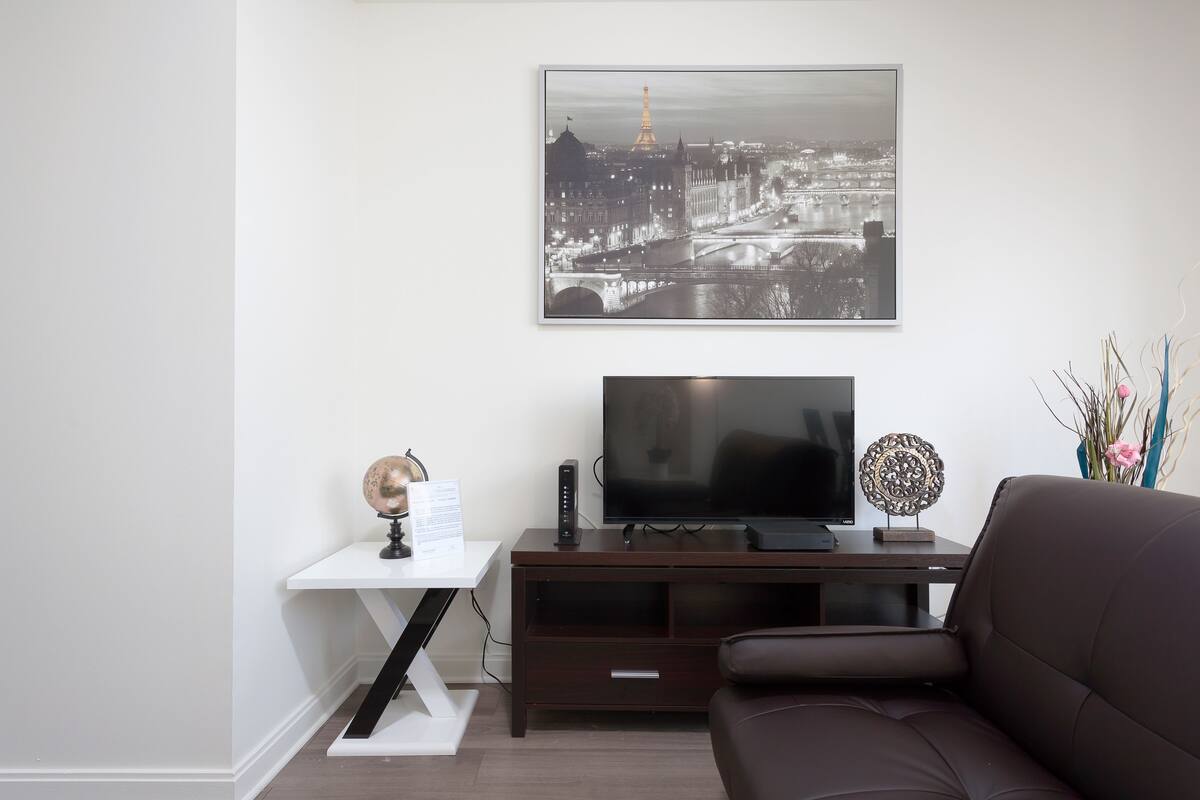 A modern living room with a flat-screen TV, a globe, and a decorative item on a wooden TV stand.