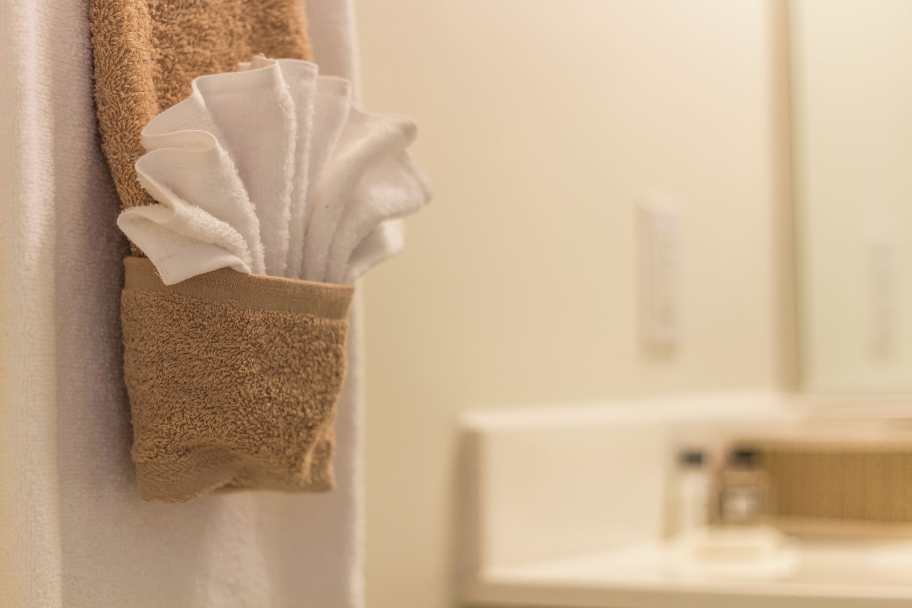 Un porte-serviettes avec une serviette pliée et une serviette marron accrochée au mur.