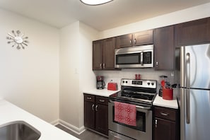 A modern kitchen with stainless steel appliances, dark wooden cabinets, and a white countertop. - Fully Furnished Apartment in Philadelphia (Philadelphia)