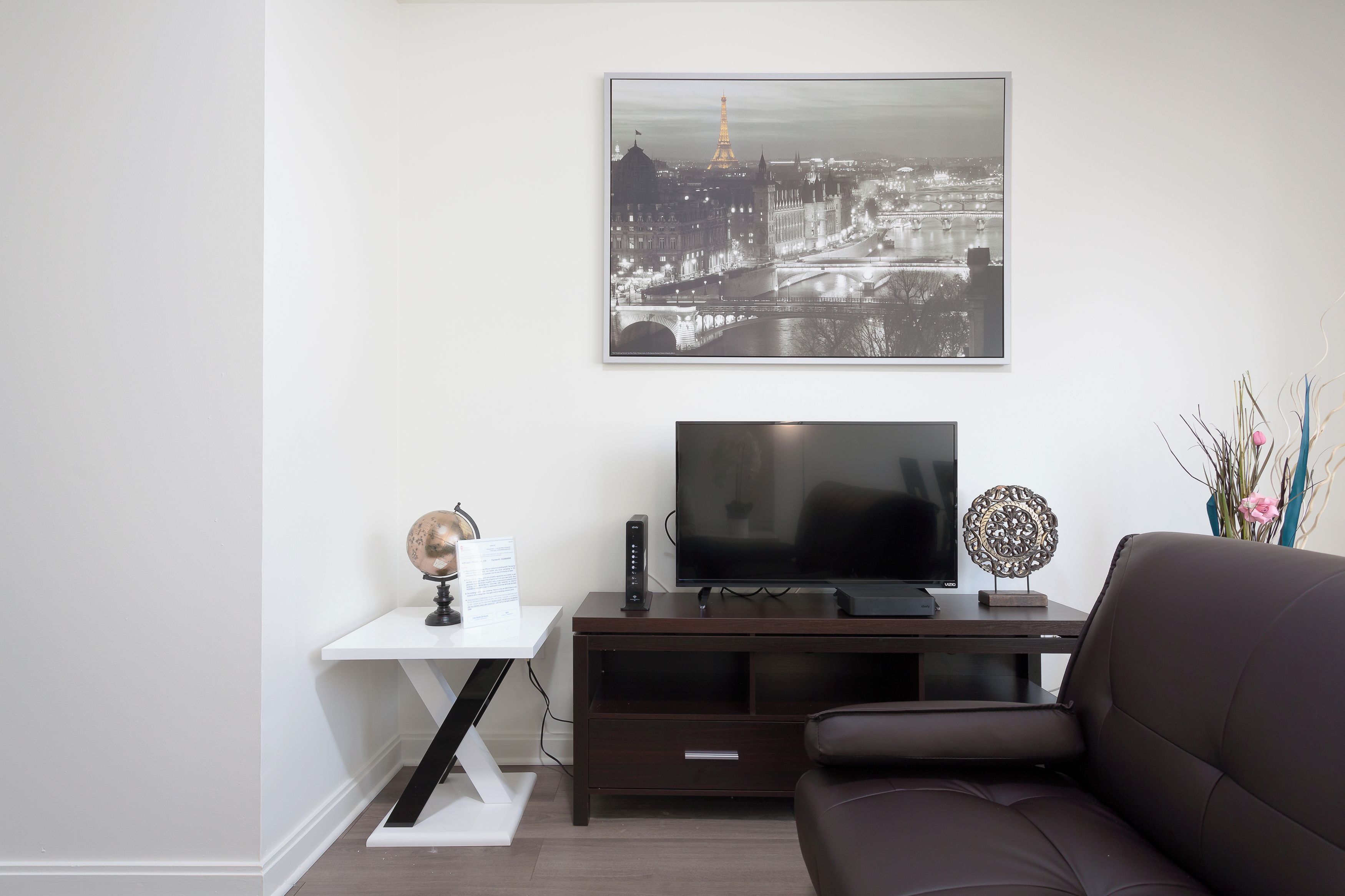 Una sala de estar moderna con un televisor de pantalla plana, un globo terráqueo y un objeto decorativo sobre un mueble bajo para televisión de madera.