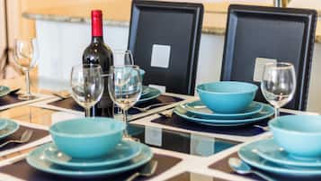 A dining table set with blue plates, bowls, and wine glasses, with a bottle of wine on the table.
