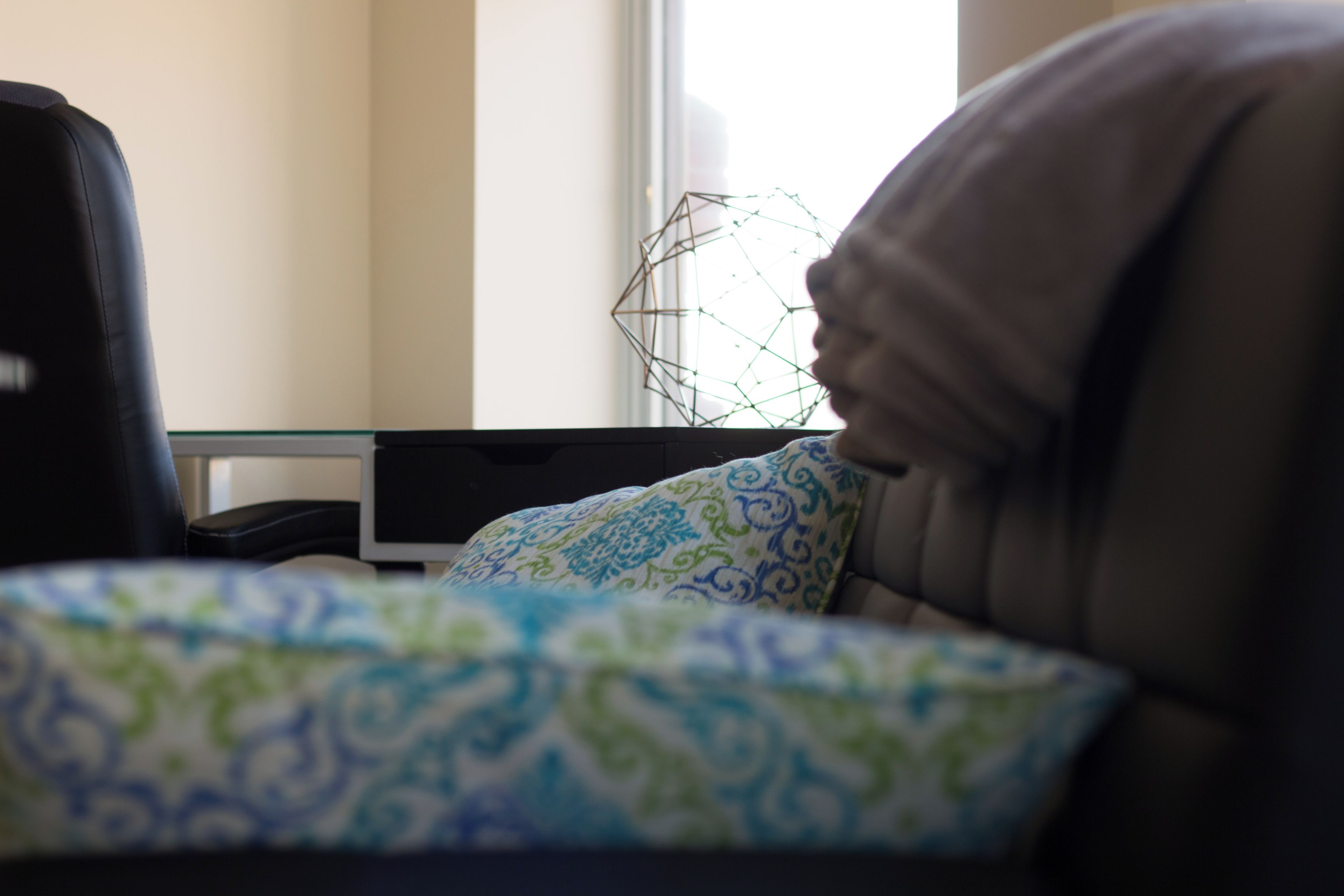 Ein Zimmer mit einem Bett, einem Sessel, einem Glastisch und einem geometrischen Dekor.