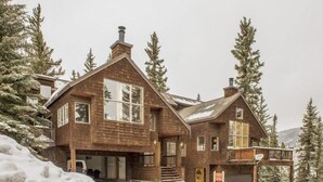 A large, two-story wooden cabin with a covered porch and a garage, surrounded by snow and tall pine trees. - Cool Ridge Town Home at Summerwood 3 Bedroom Holiday home by Key to the Rockies (Dillon)