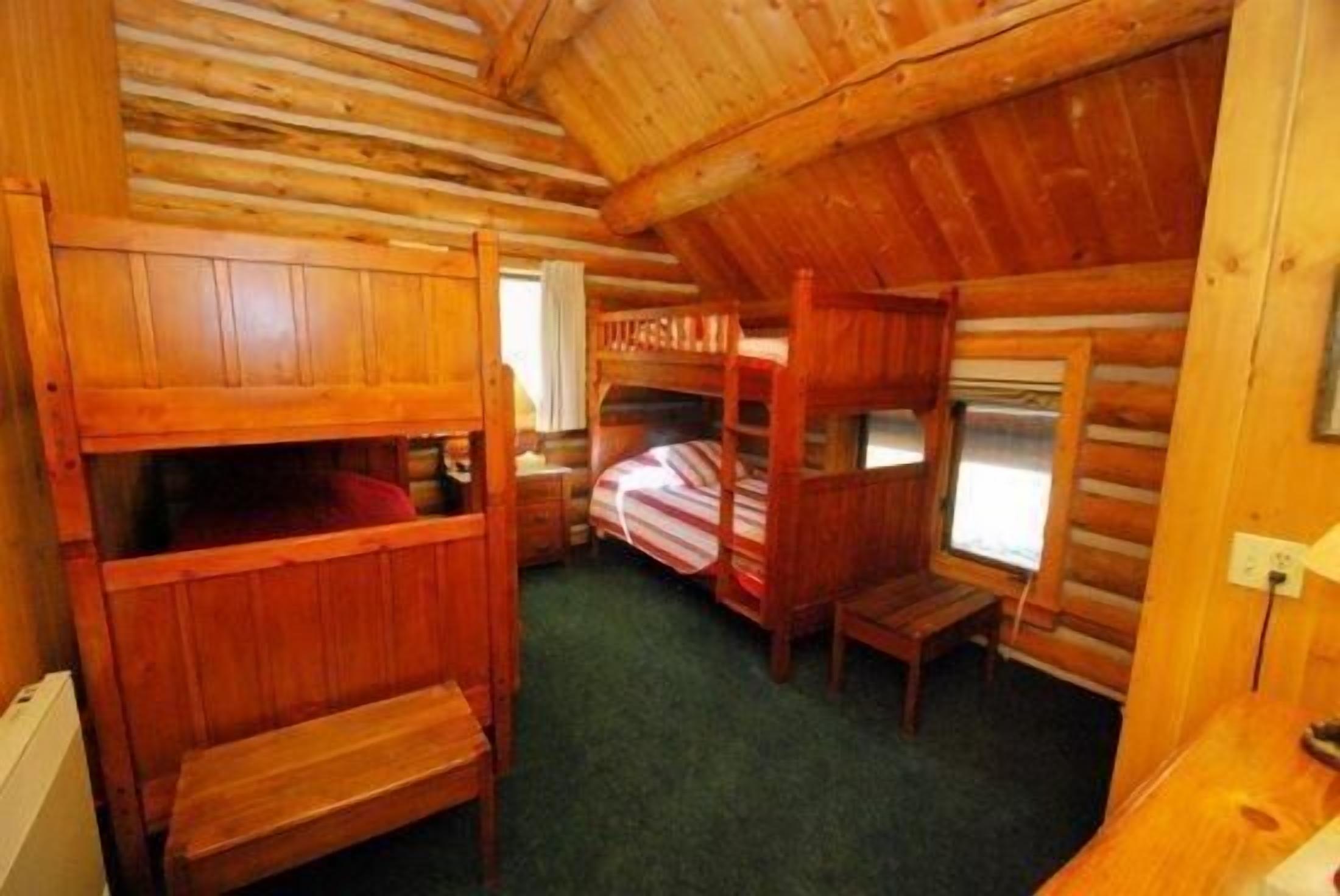A cabin with bunk beds, a small table, and a window.