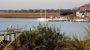 A marina with several boats docked, a wooden pier, and a building with a red roof in the background. - Turtle Bay 10 3 Bedroom Holiday Home By My Ocean Rentals (Folly Beach)