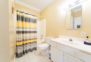 A bathroom with a striped shower curtain, a toilet, a sink, and a mirror. - Pavilion Watch 2B 3 Bedroom Holiday Home By My Ocean Rentals (Folly Beach)