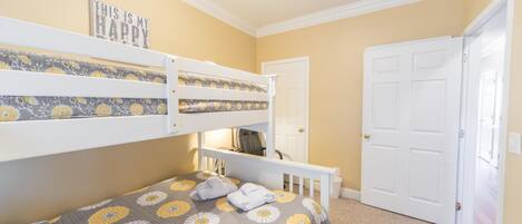 A bedroom with bunk beds, a door, and a carpeted floor.