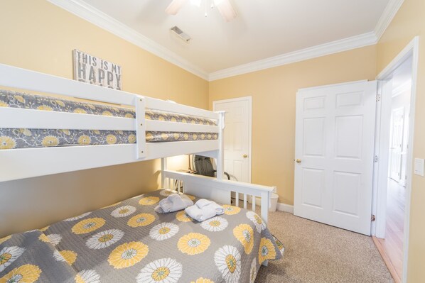 A bedroom with bunk beds, a door, and a carpeted floor. - Pavilion Watch 2B 3 Bedroom Holiday Home By My Ocean Rentals (Folly Beach)