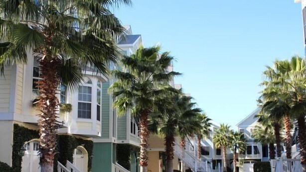 A row of coastal-style houses with white railings and palm trees. - Waters Edge 113 Community 3 Bedroom Holiday Home By My Ocean Rentals (Folly Beach)