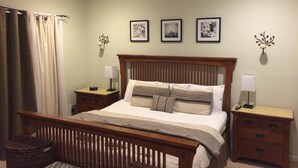 A bedroom with a bed, nightstands, a wooden headboard, a ceiling fan, and wall-mounted lamps. - Waters Edge 113 Community 3 Bedroom Holiday Home By My Ocean Rentals (Folly Beach)
