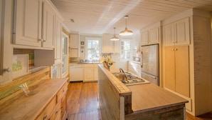 A kitchen with wooden cabinets, a central island, and pendant lighting.
