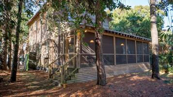 A rustic wooden cabin with a screened porch and a staircase leading to the entrance.