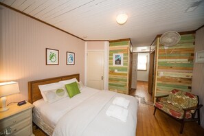 Ein Hotelzimmer mit einem hölzernen Bett, einem Nachttisch mit Lampe, einem Stuhl mit Blumenmuster und einer Wand mit Streifenmuster.