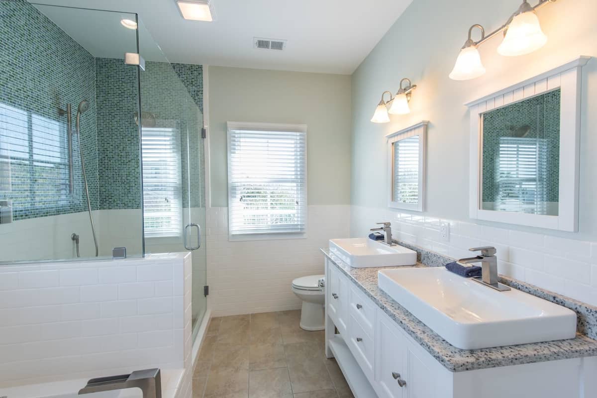 A modern bathroom with a glass-enclosed shower, a white toilet, and a vanity with a sink and mirror.