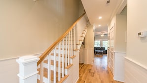 Un interior moderno con una escalera de madera, paredes blancas y suelo de madera.