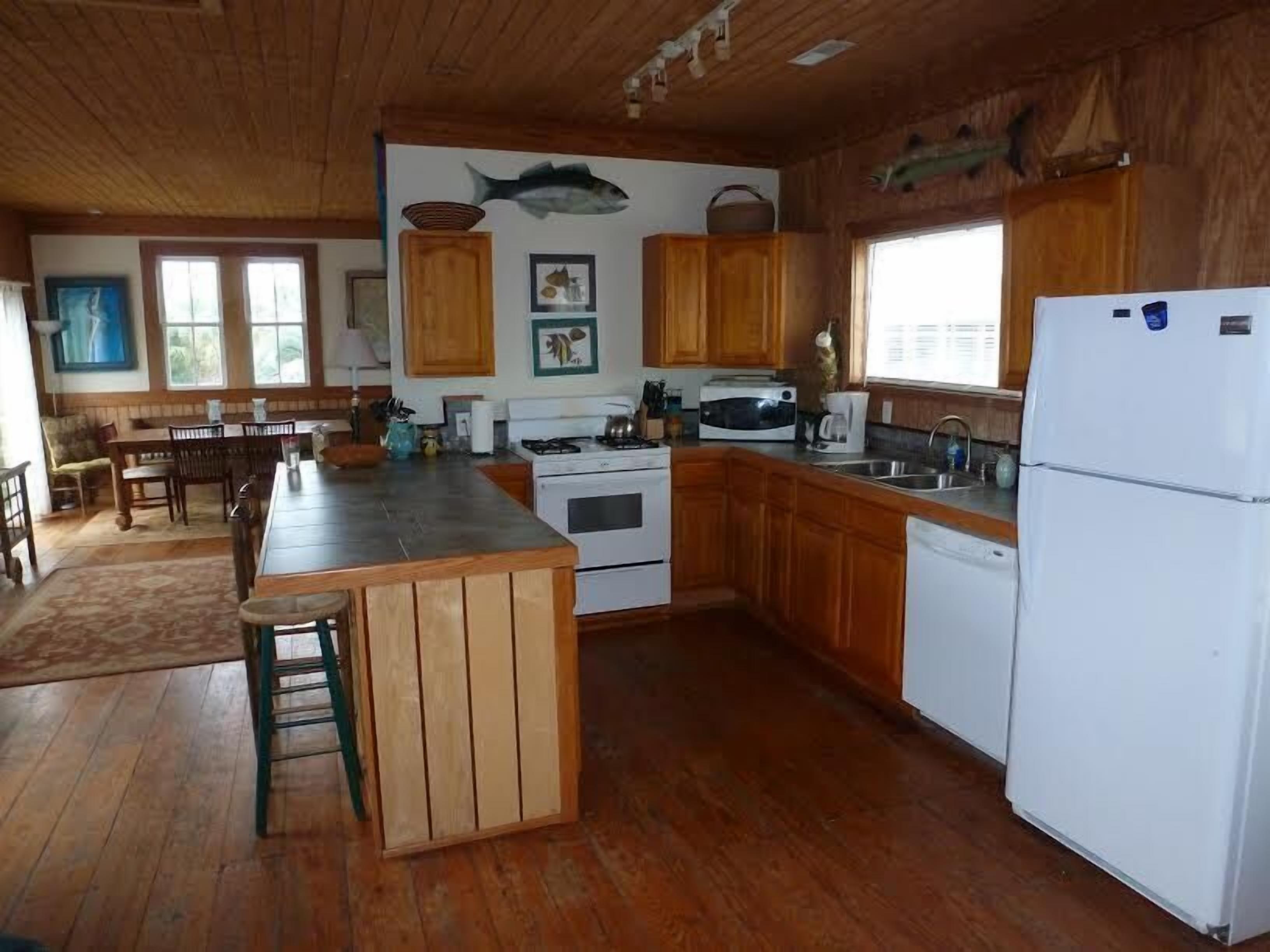 A kitchen with wooden cabinets, a stove, a refrigerator, and a dining area with chairs and a table.