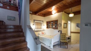 A bedroom with a wooden staircase, a bed, a chair, a bookshelf, and a window with blinds. - E Ashley 1634 4 Bedroom Holiday Home By My Ocean Rentals (Folly Beach)