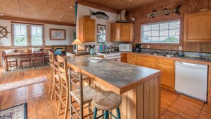 A spacious kitchen with wooden cabinets, a large island with stools, and a view of the outdoors through the windows. - E Ashley 1634 4 Bedroom Holiday Home By My Ocean Rentals (Folly Beach)