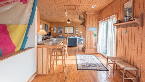 A wooden interior with a kitchen area, a dining table, and a bar. - E Ashley 1634 4 Bedroom Holiday Home By My Ocean Rentals (Folly Beach)