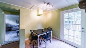 Zona pranzo con tavolo e sedie, una lampada a sospensione e una porta con finestra.