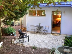 Eine Terrassenfläche mit Tisch, Stühlen, einem Ventilator und Topfpflanzen.