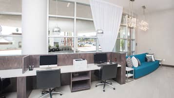 A modern office space with a long desk, two computers, and a blue sofa.
