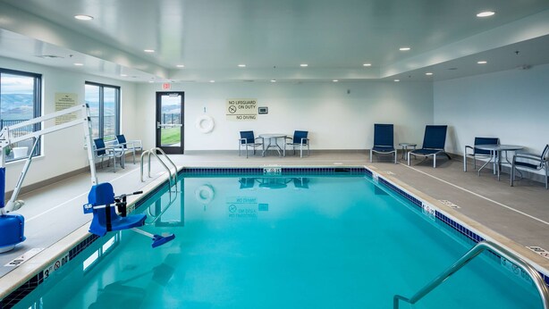 An indoor swimming pool with blue chairs and a lifeguard stand.