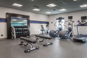 A gym with weight benches, dumbbells, treadmills, and exercise bikes.