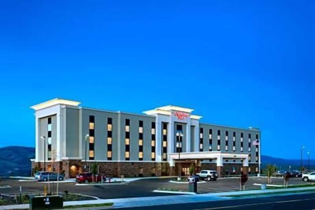 A hotel with a modern design, a central entrance, and a parking lot.