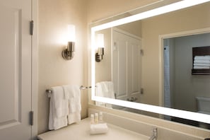 A bathroom with a large mirror, white towels, and a sink with toiletries. - Homewood Suites by Hilton Concord Charlotte (Concord)
